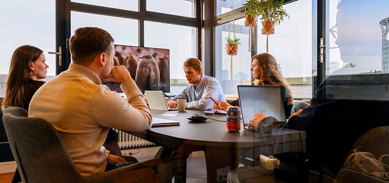 Groep collega's zit samen aan tafel in een meeting