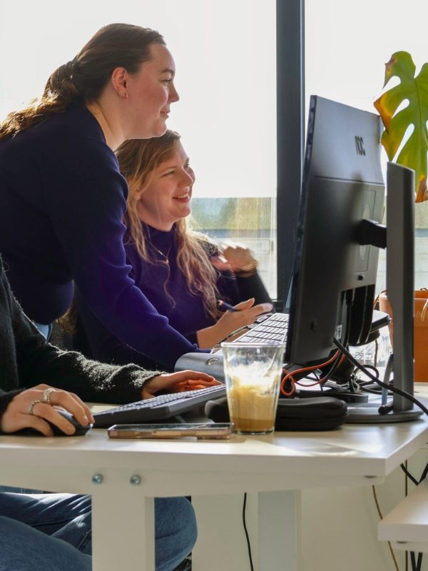 Loes en Kirstin kijkend naar een computer Loes en Kirstin kijkend naar een computer